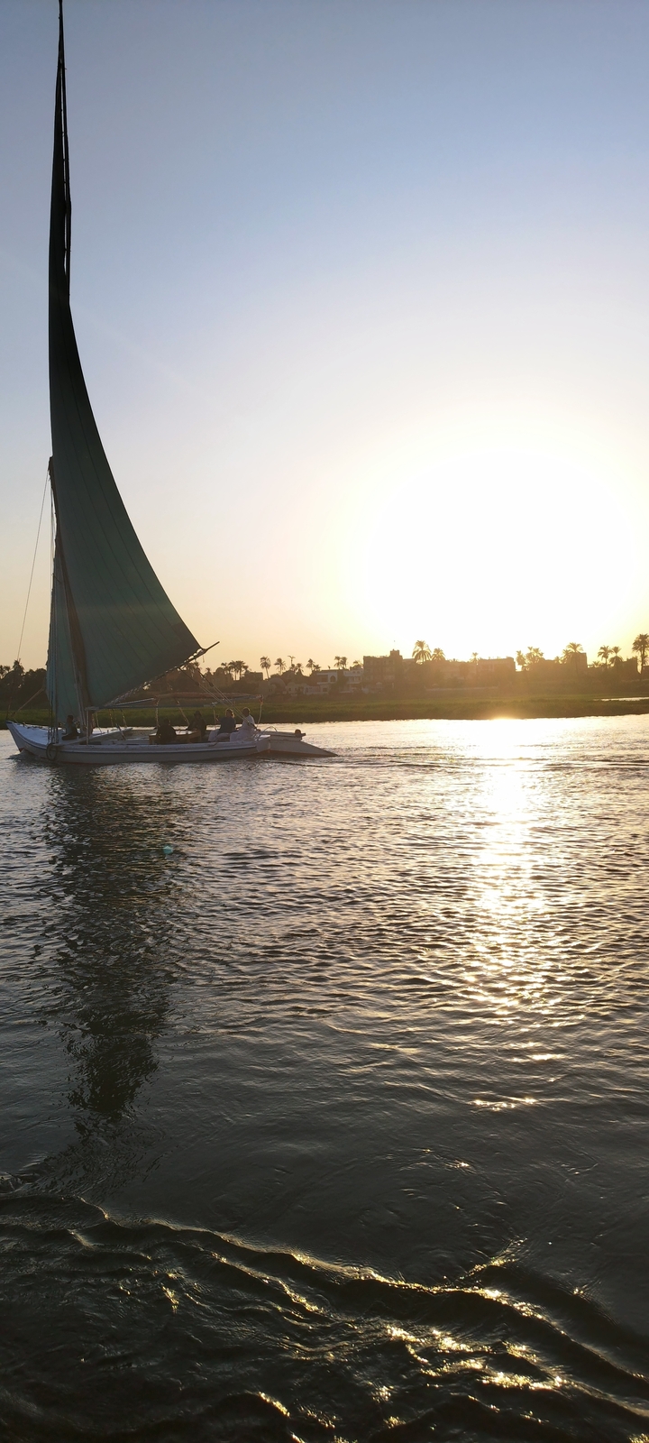 Group of people sailing on a traditional boat at sunset.