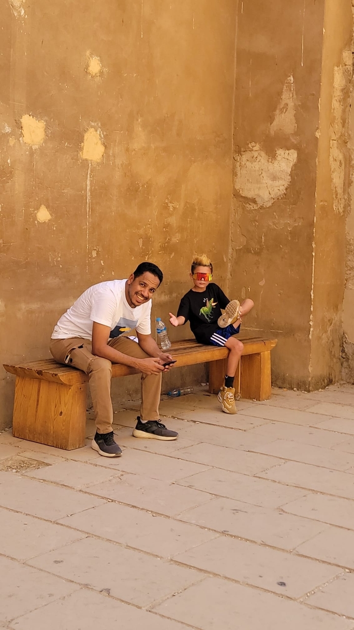 Father and son sitting on a bench in an ancient site.