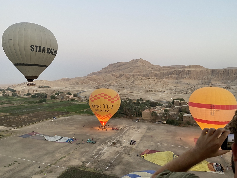 Heteluchtballonnen bij zonsopgang boven een landschap met bergen.