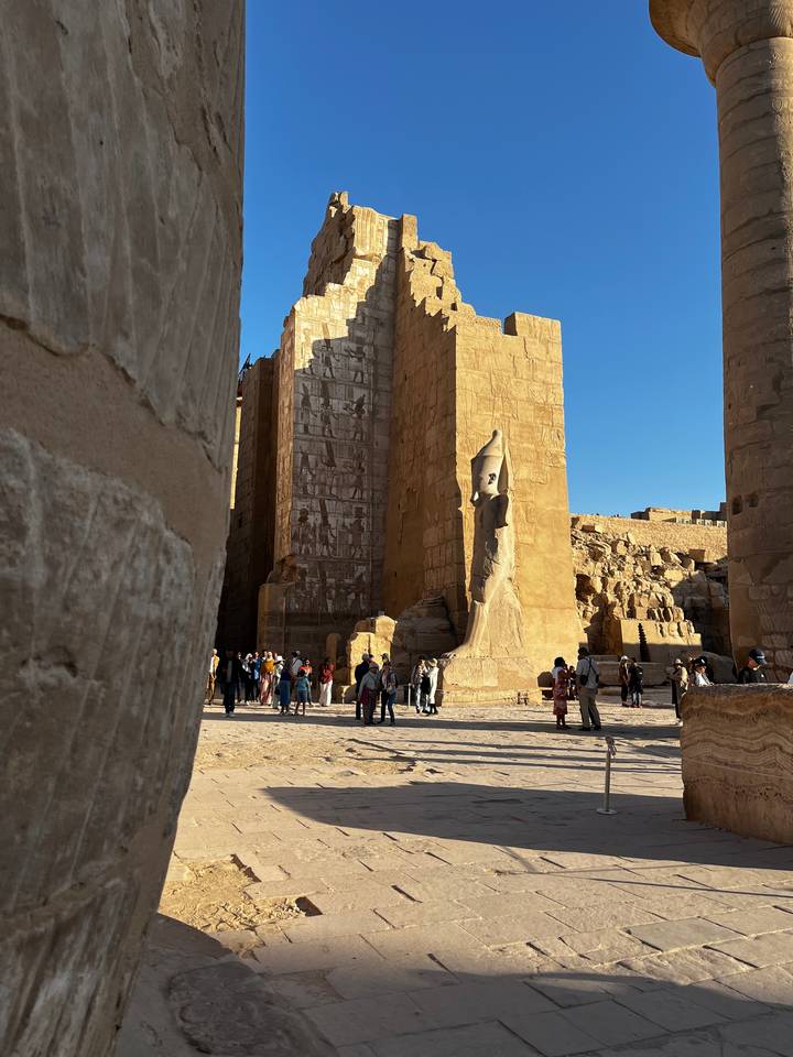 Ruins of an ancient Egyptian temple with people walking around.