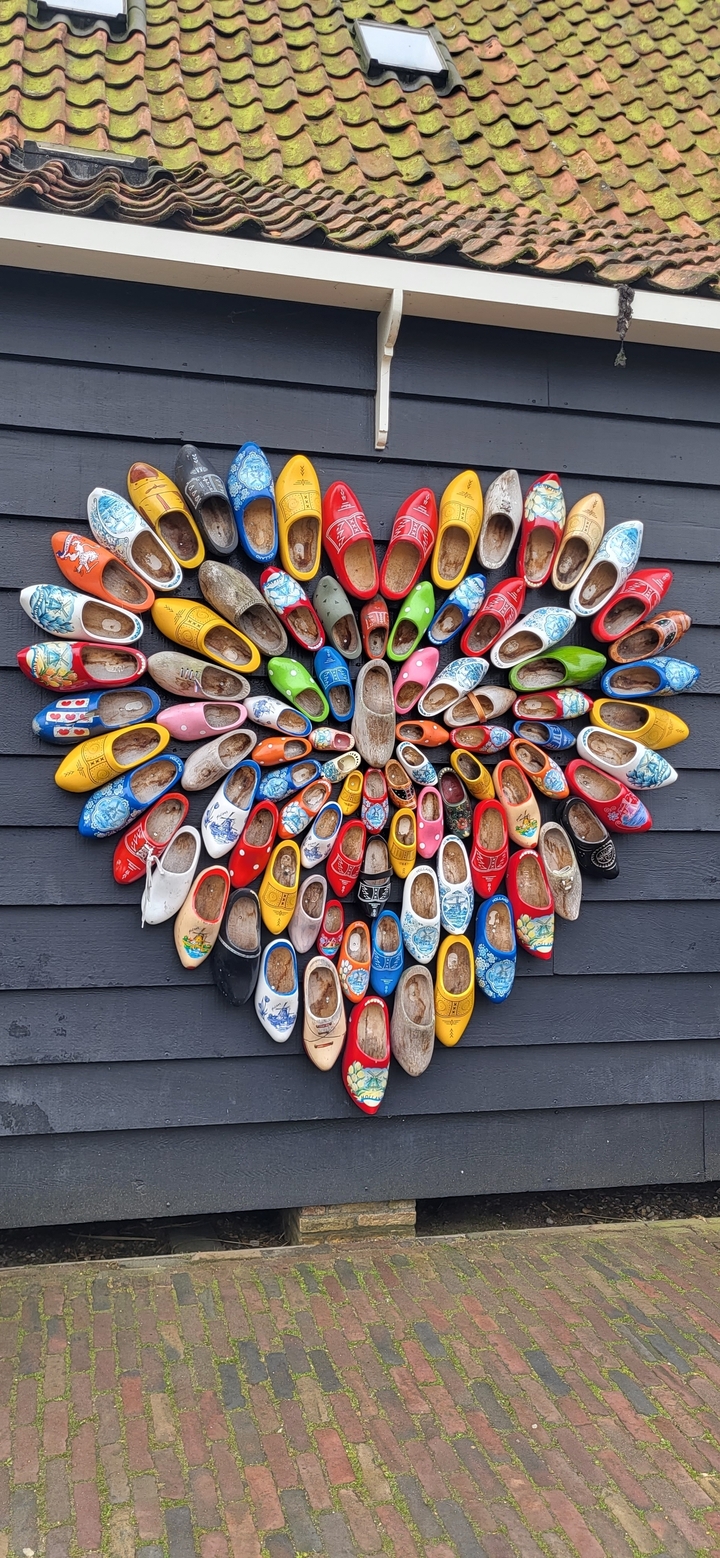 Colorful wooden clogs arranged in a circle on a wall.