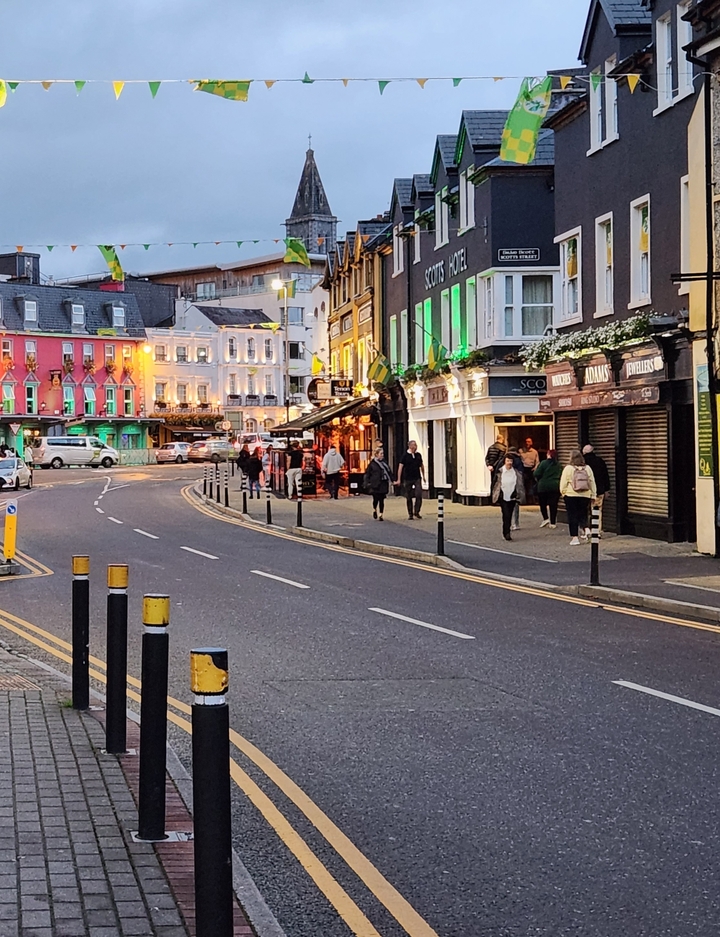 People walking in a lively street with colorful buildings and lights.