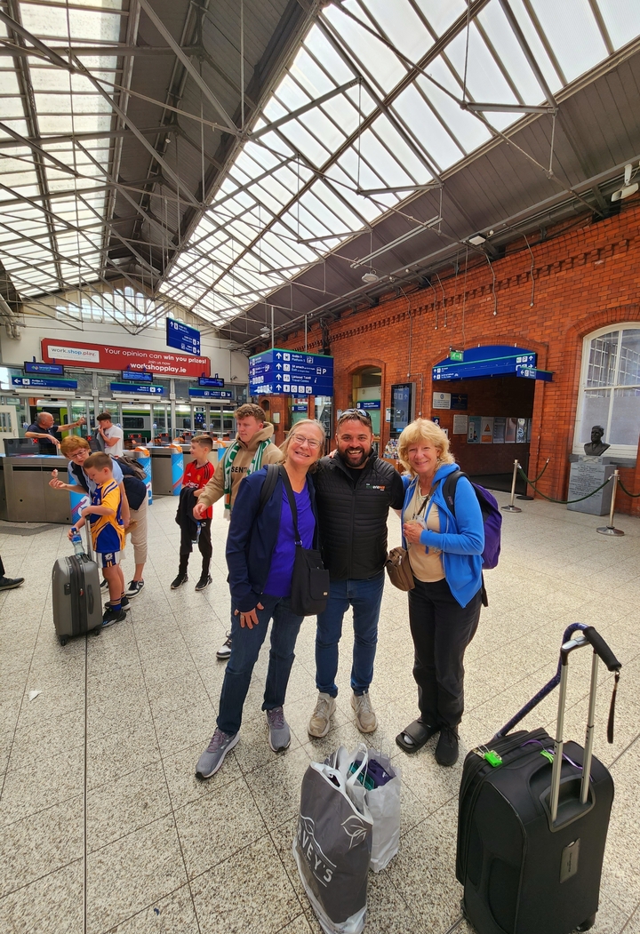 Group of travelers at a train station posing for a group photo.