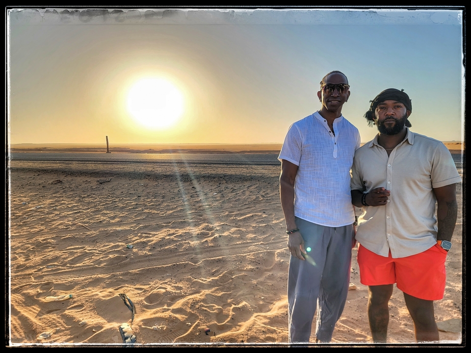 Two men posing at sunset in a desert landscape, photo has a frame effect.