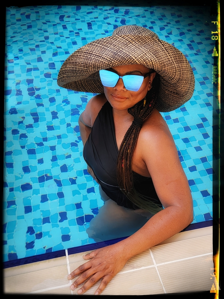 Woman in a pool wearing a hat and sunglasses, photo has a frame effect.