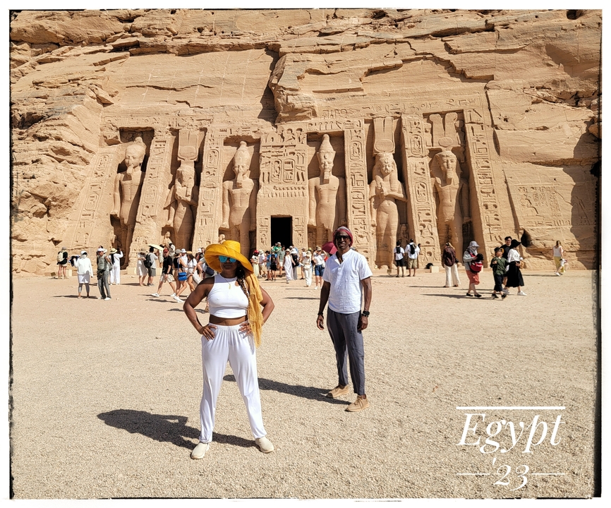 People posing in front of the Abu Simbel temple with inscriptions.