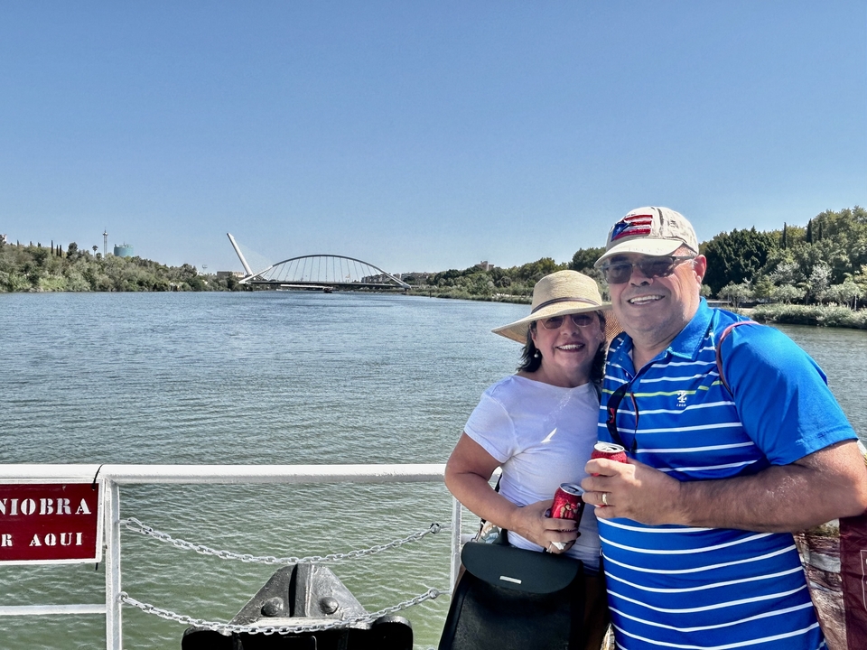 Couple posing by a river with a bridge in the background.