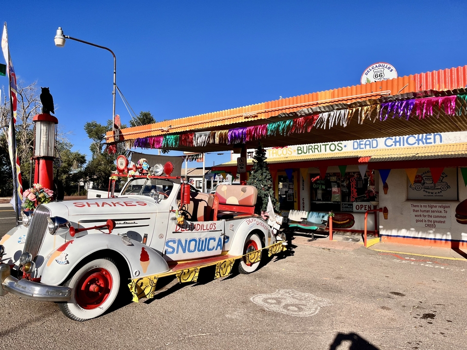 Vintage diner with a colorful classic car and Route 66 sign.