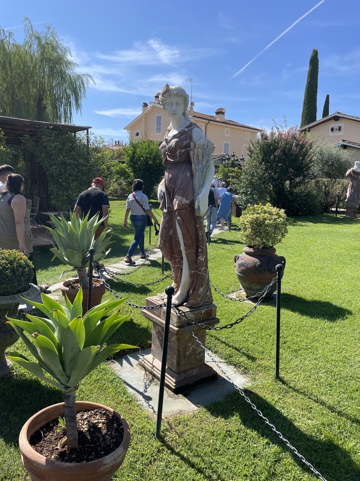 Tourists walking in a garden with classical statues.