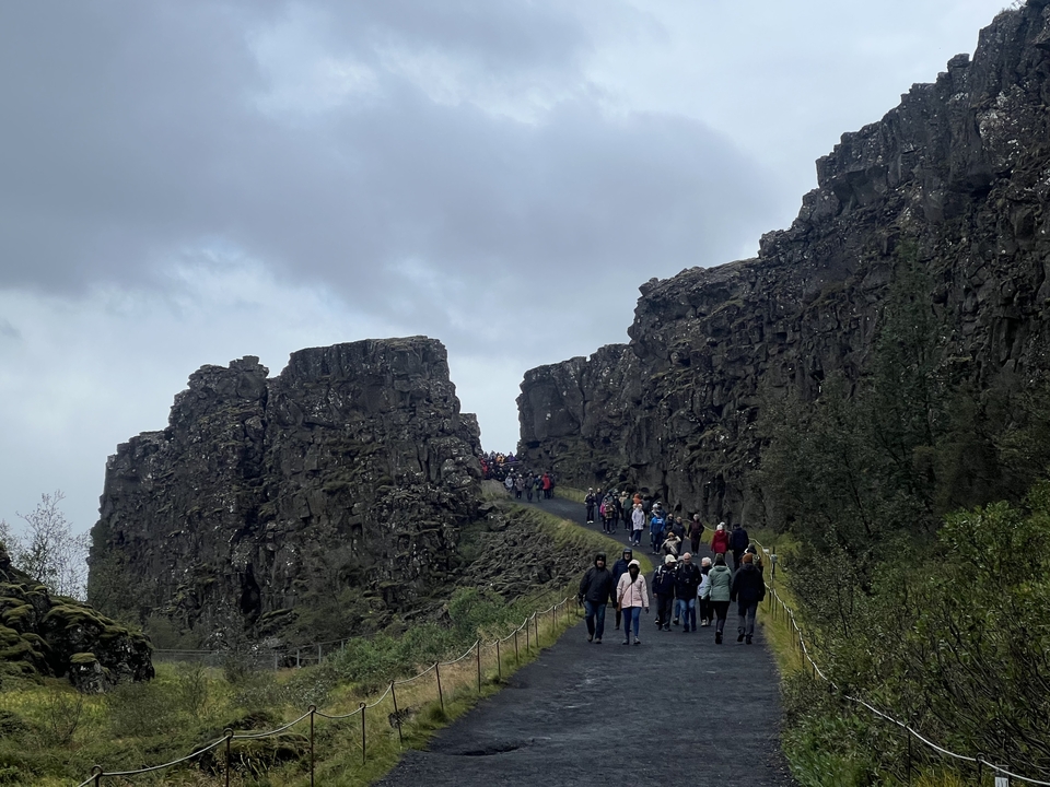 Crowd walking through a narrow canyon path.