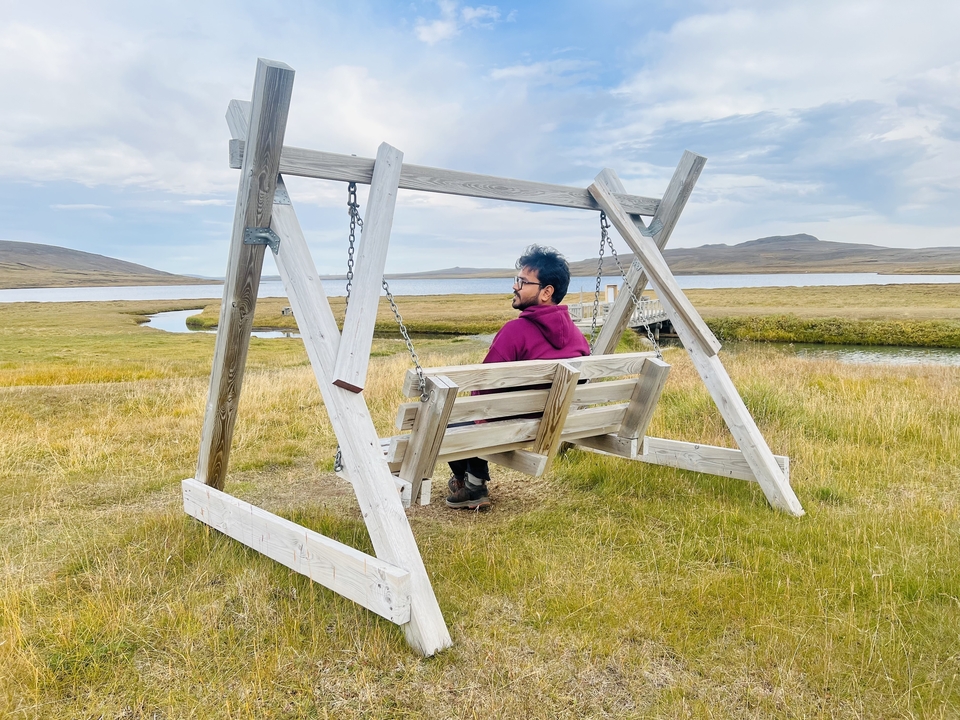A person sitting on a swing with an open landscape.