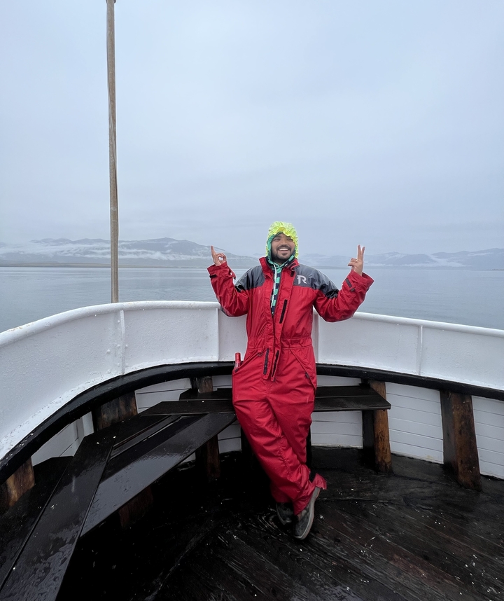 Man posing on a boat with misty mountains.