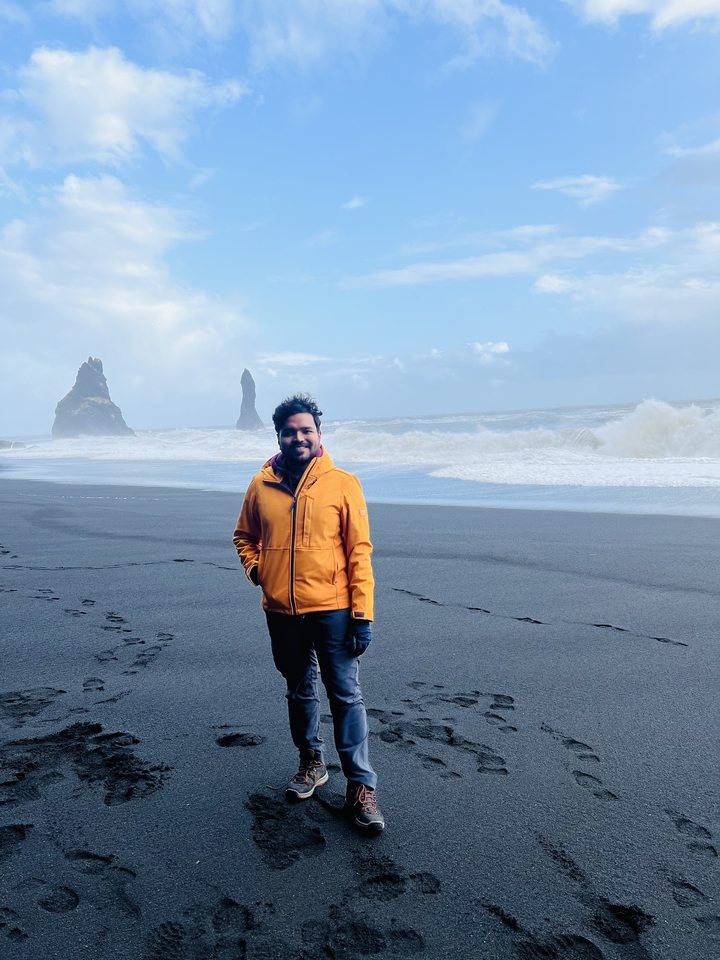 Man on a volcanic black sand beach.