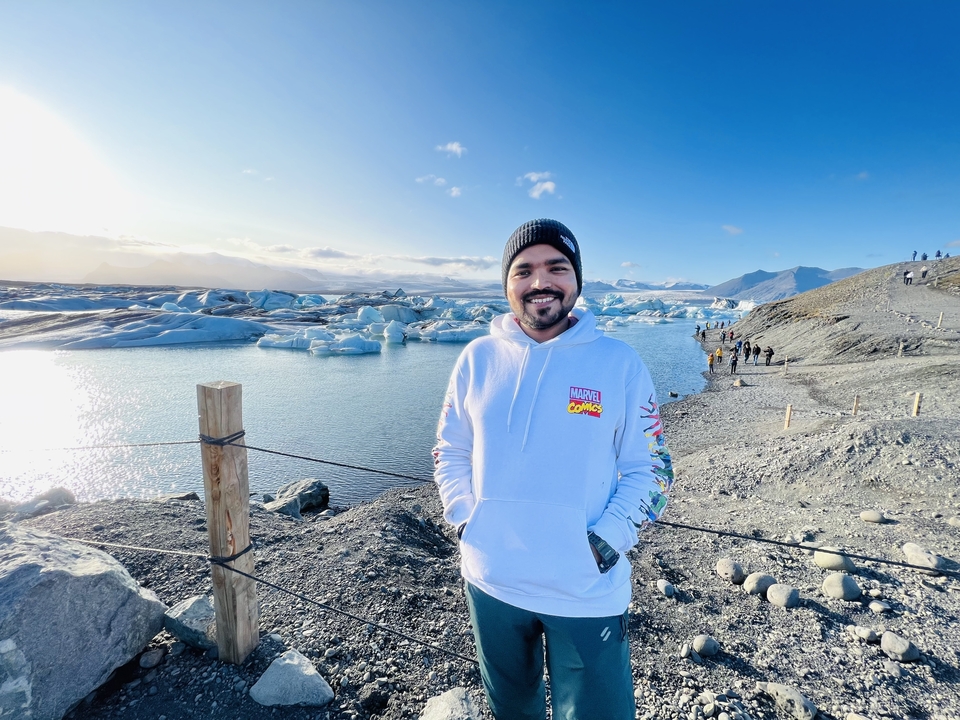 A person standing in front of a glacial lagoon with icebergs.