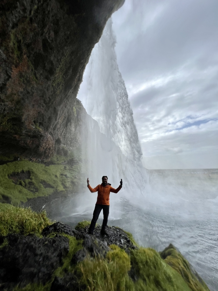 Man near waterfall with mist in Iceland.