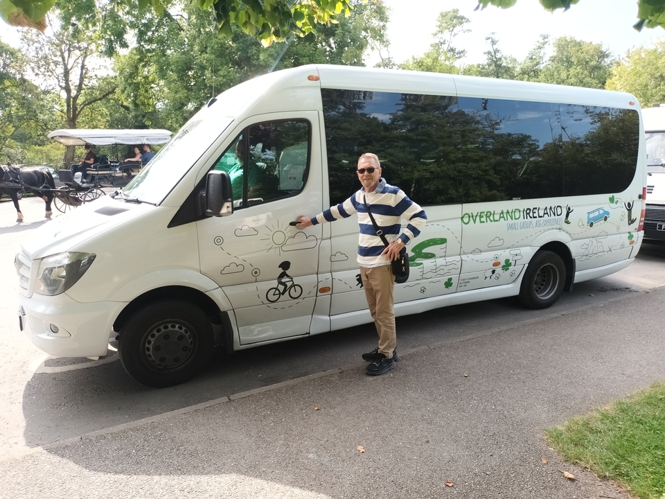 Un homme prenant la pose à côté d'un véhicule de tourisme en Irlande.