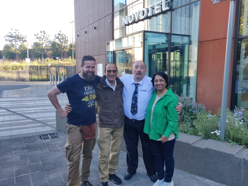 Four people posing together outside a modern building.