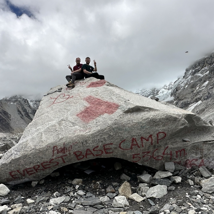 Two people posing on a rock at Everest Base Camp.