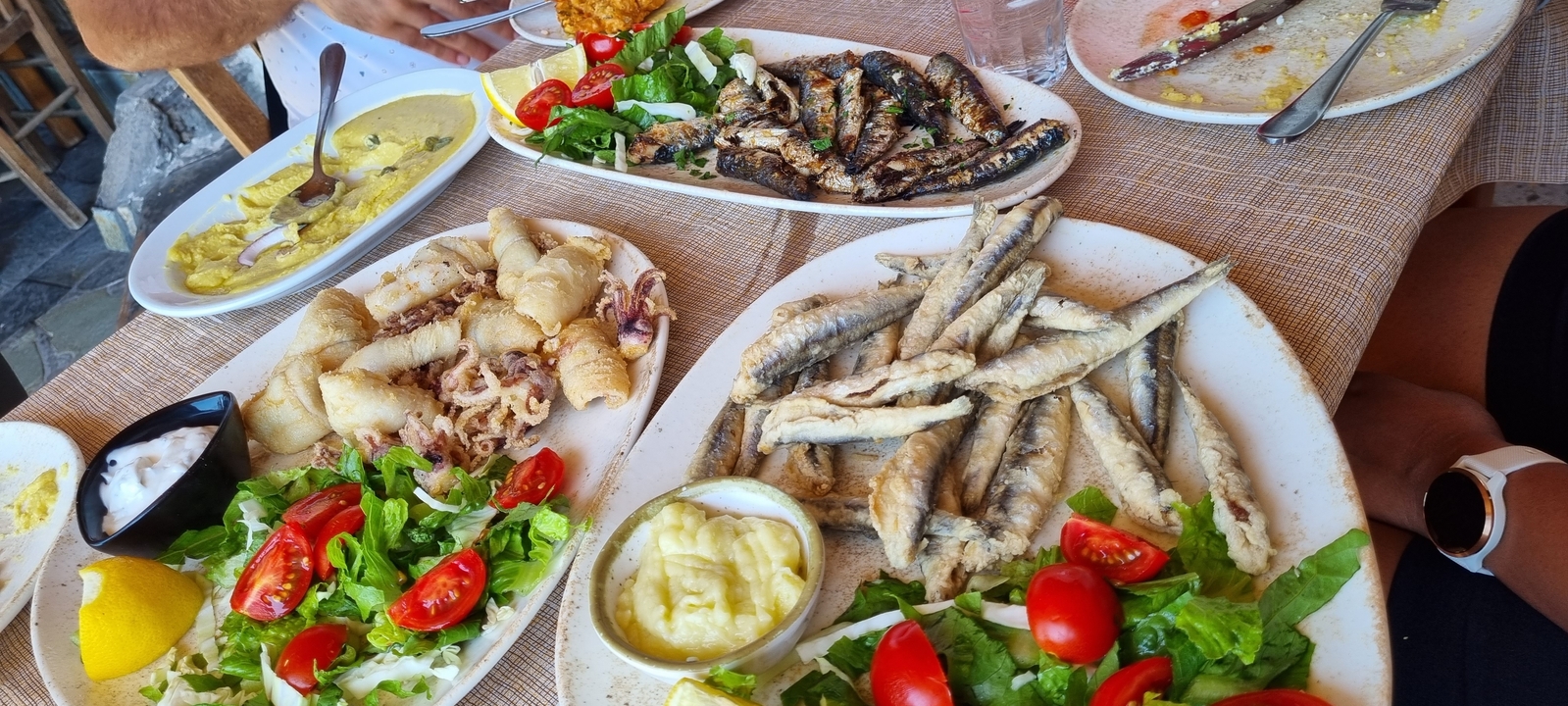 Assorted plates of seafood and salads on a table.