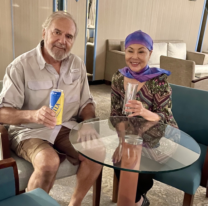 Two people sitting at a glass table with drinks.