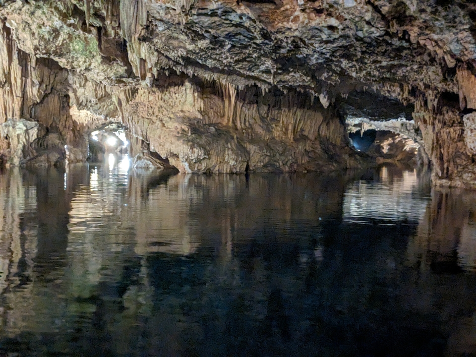 Cave with stalactites reflected on water.