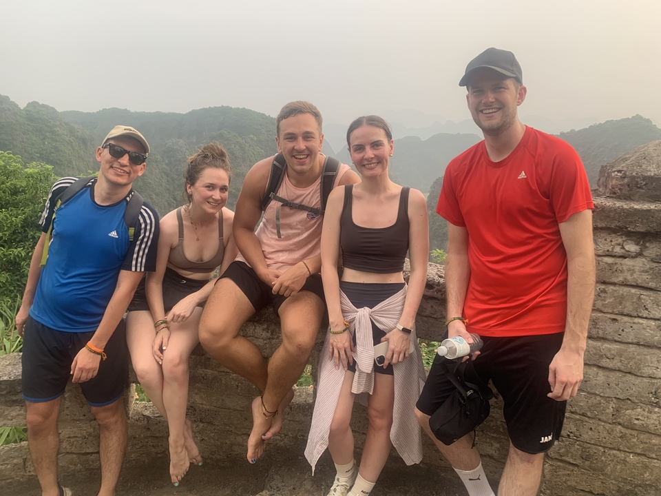 Group of friends posing in front of a lush mountainous landscape.