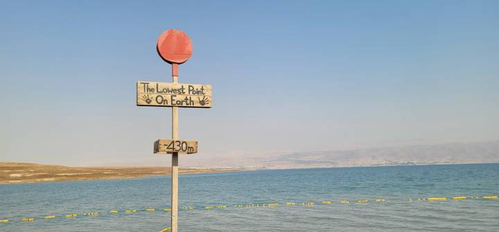 A sign reading 'The Lowest Point On Earth' by the Dead Sea.