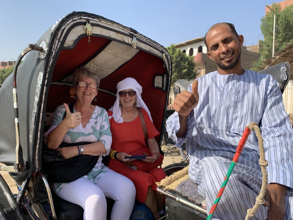 Three people on a carriage with driver, all showing thumbs up.
