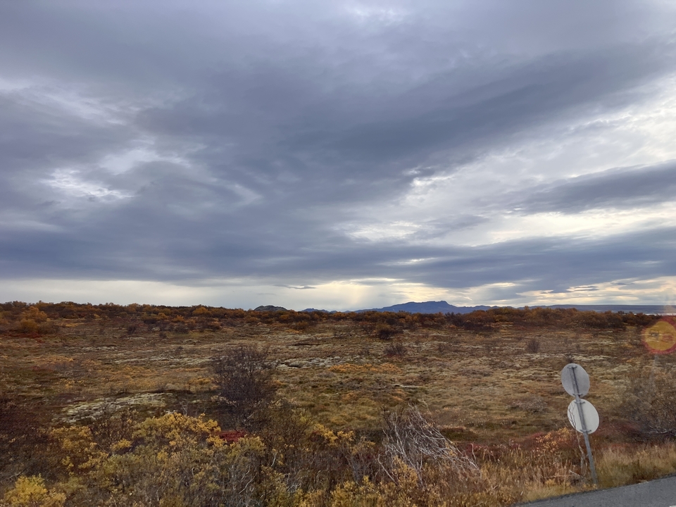 Cloudy sky above a vast, flat landscape with sparse vegetation.