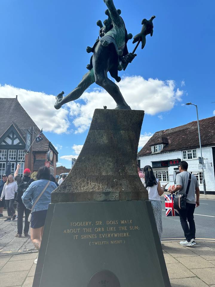 Statue with an inscription, people in the background.