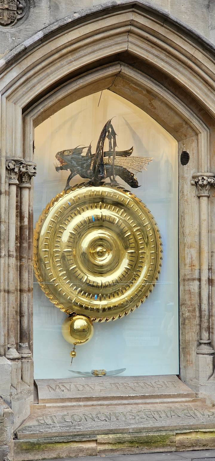 A golden clock with a dragon motif displayed behind glass.