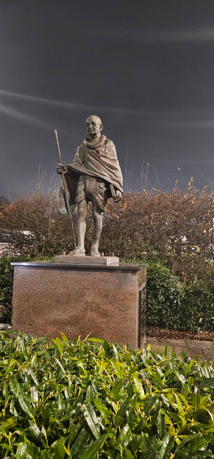 A statue of a historical figure holding a staff at night.