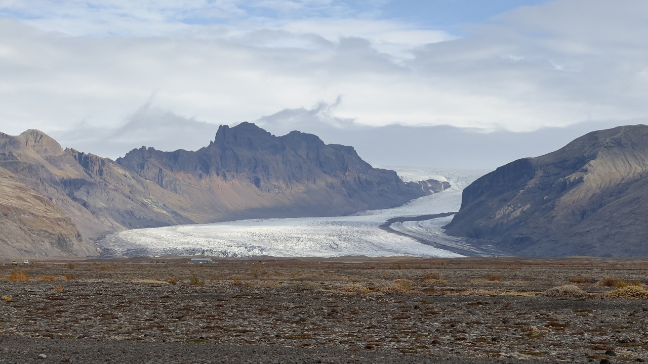 Distant view of a glacier surrounded by rocky mountains.