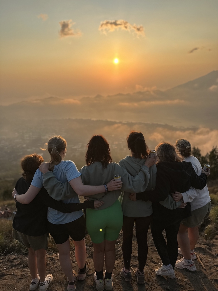 A group of people watching a sunset on a hill.