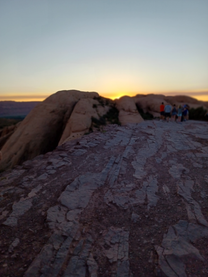 People on a rocky terrain at sunset.