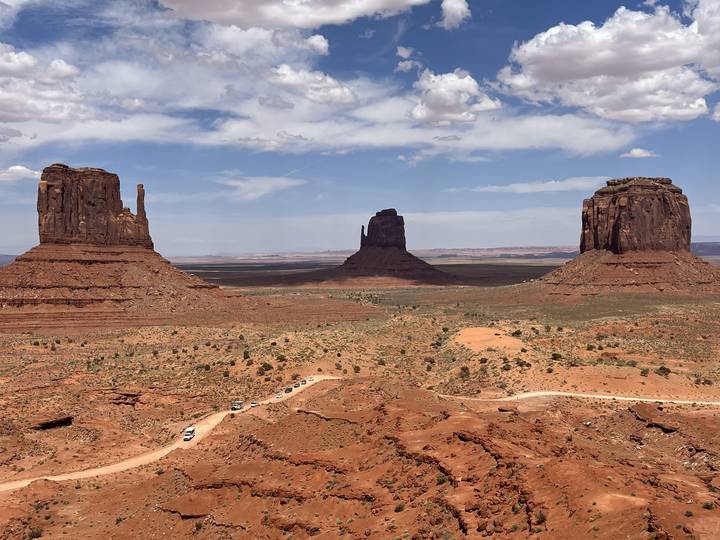 Mesa view in a desert landscape with red rock formations and a distant road.