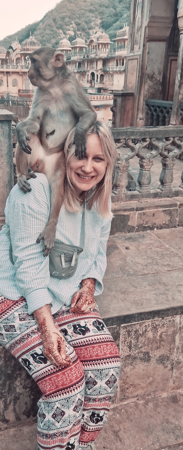 Gros plan d'une personne souriante avec le bras d'un singe autour d'elle.