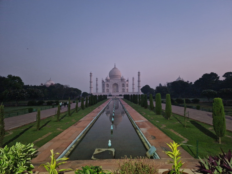 Vue du Taj Mahal au crépuscule avec un bassin réfléchissant.