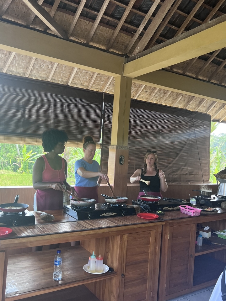 Women cooking in an open-air setting with greenery.