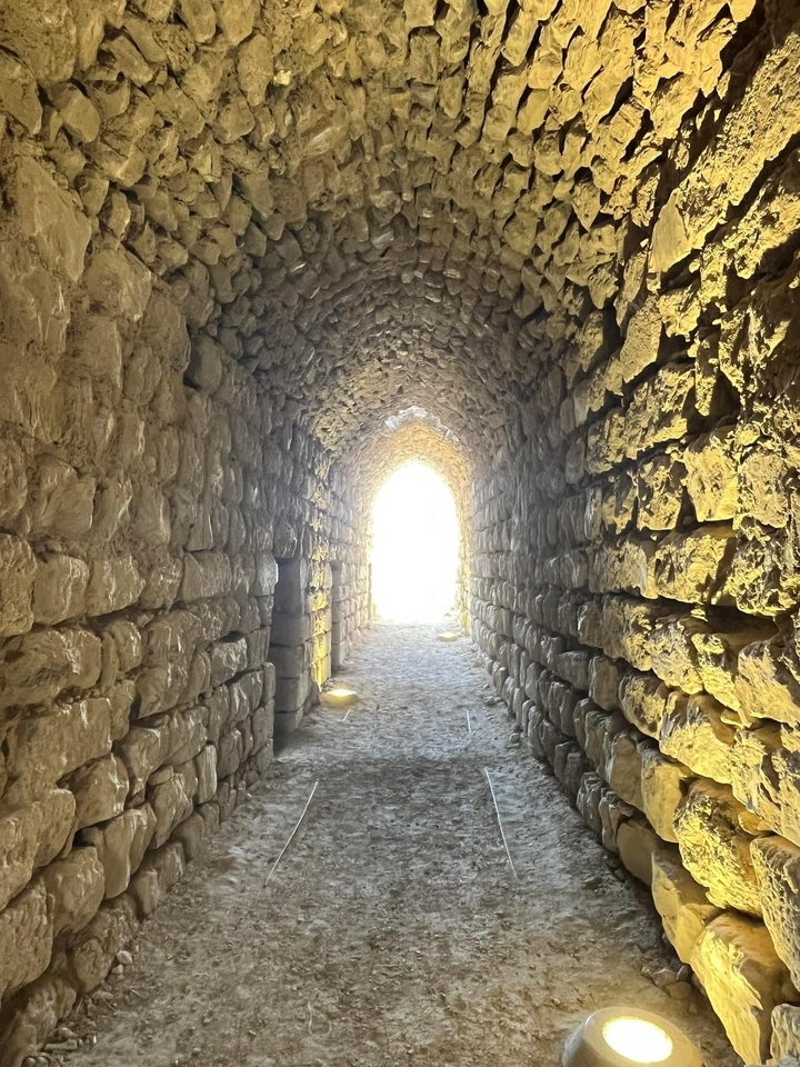 Stone corridor with sunlight at the end.