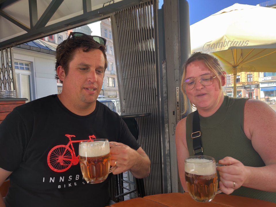 Two people enjoying beers at a cafe.