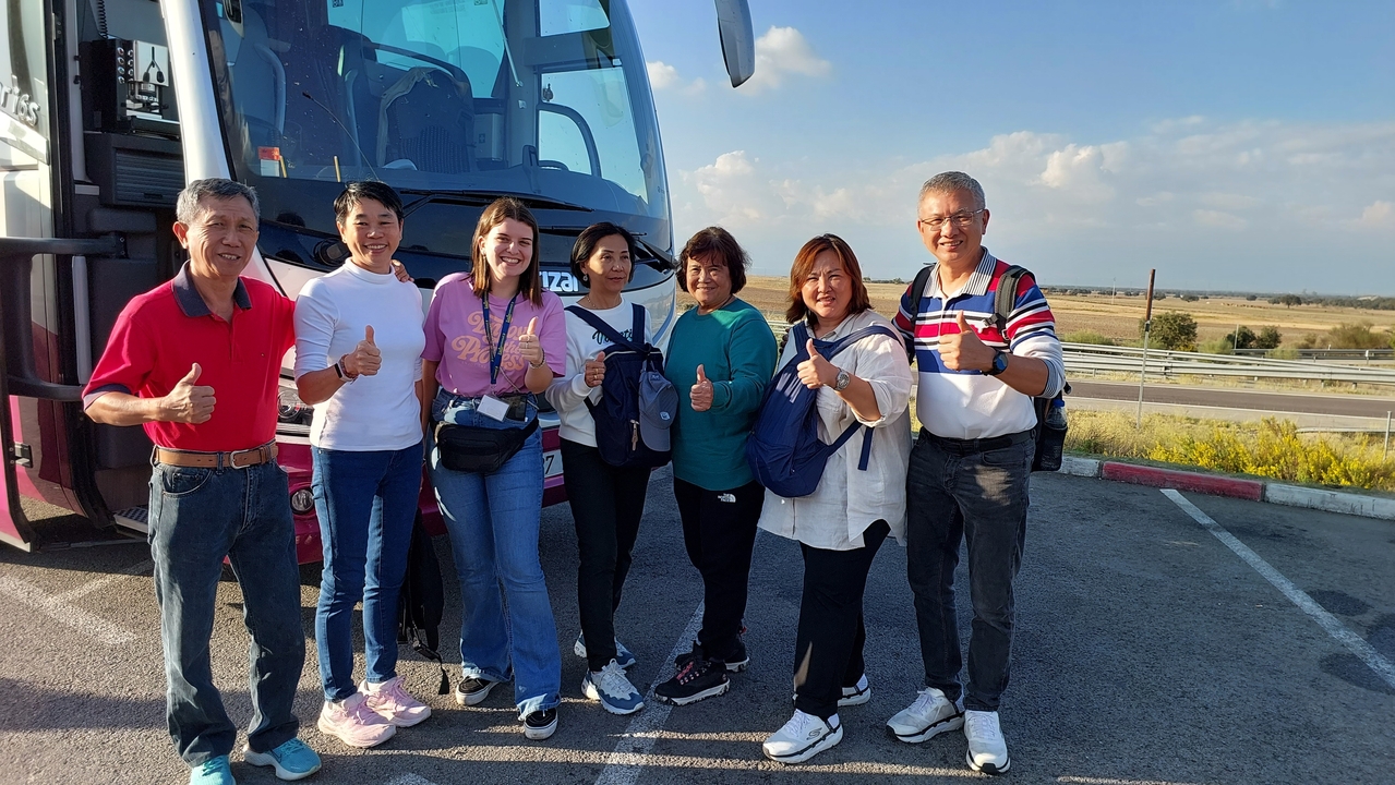Group of tourists posing in front of a bus.