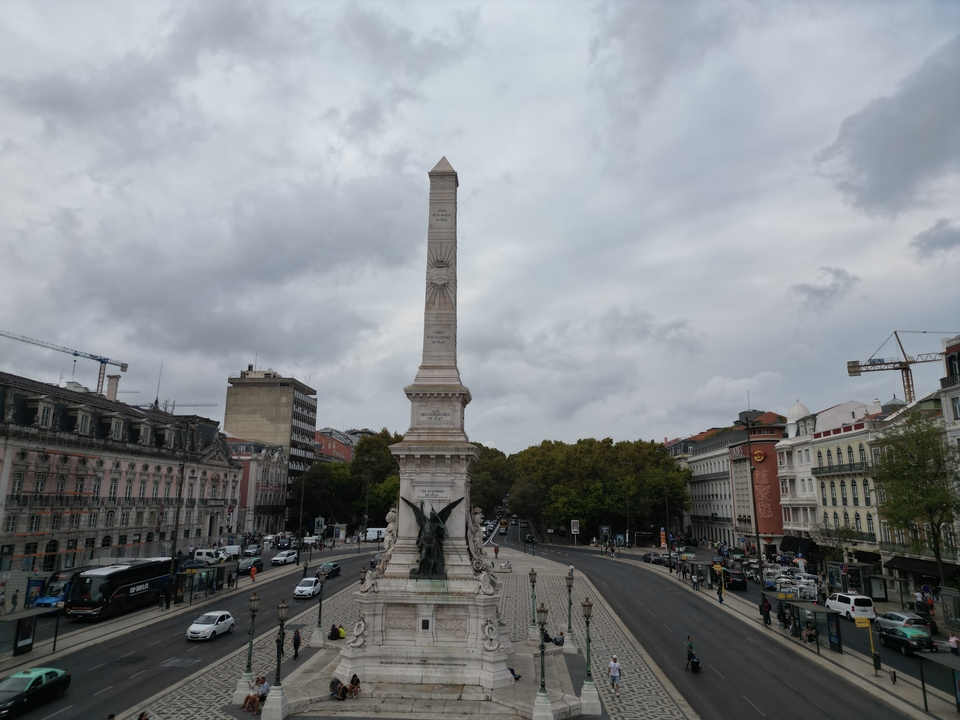 Central monument in a city square with traffic.