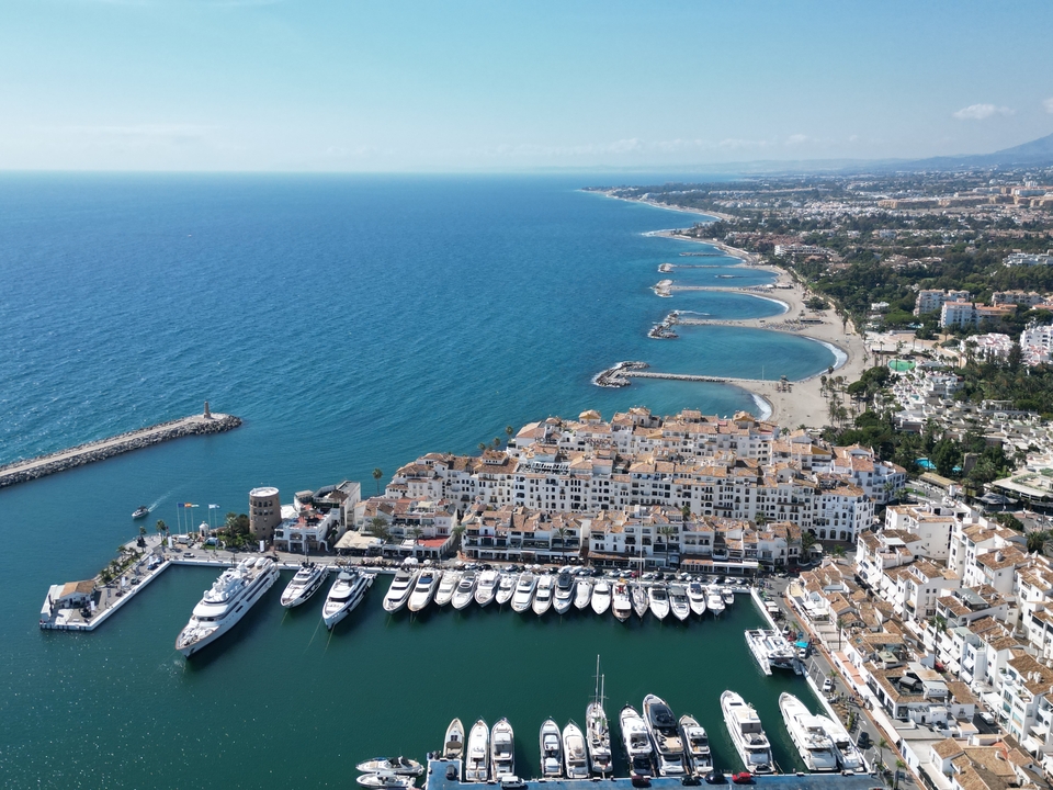 Aerial view of a marina with boats and a beach in the background.