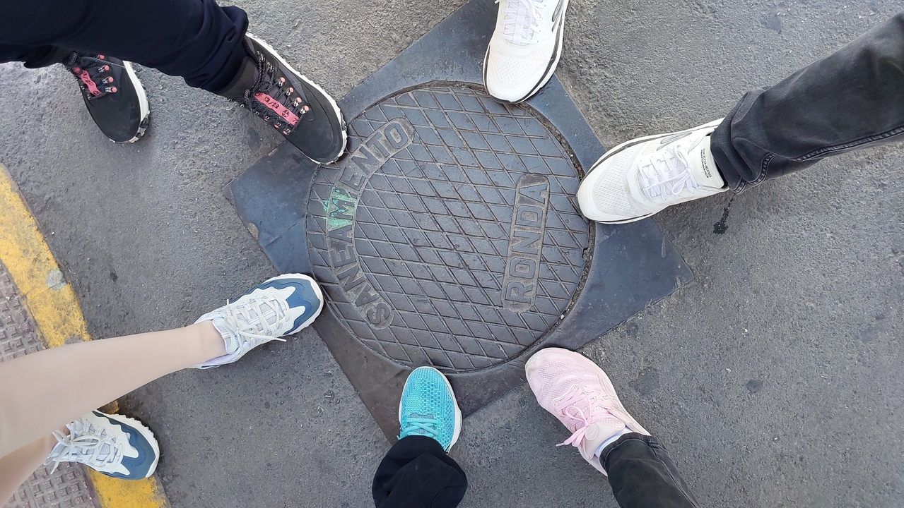 Close-up of a group of people standing around a manhole cover.