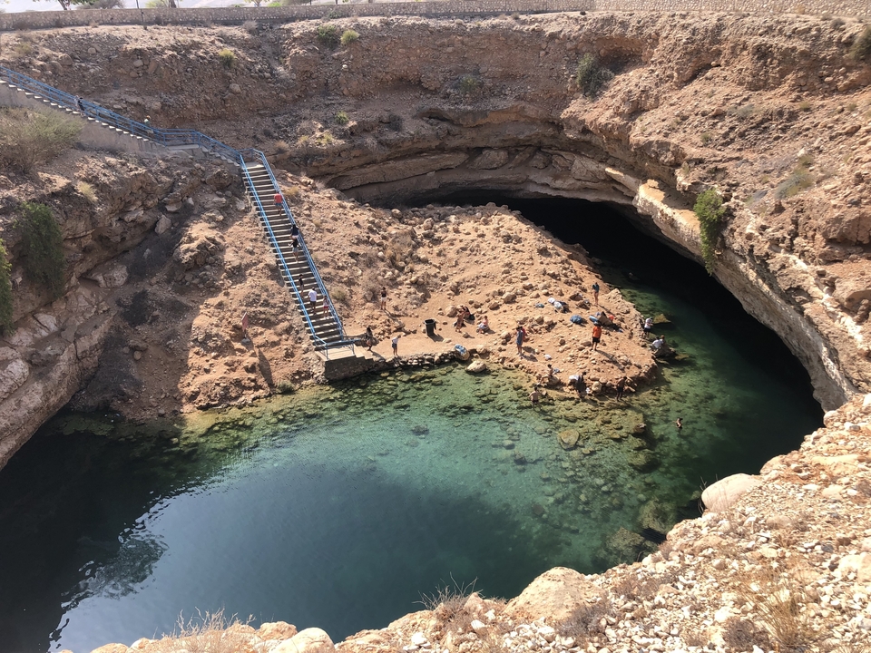 Natural sinkhole filled with water and surrounded by rocks.