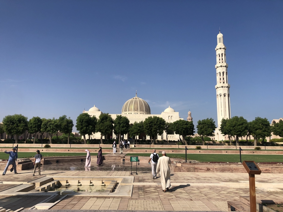 Mosque with a large dome and two minarets, people walking around.