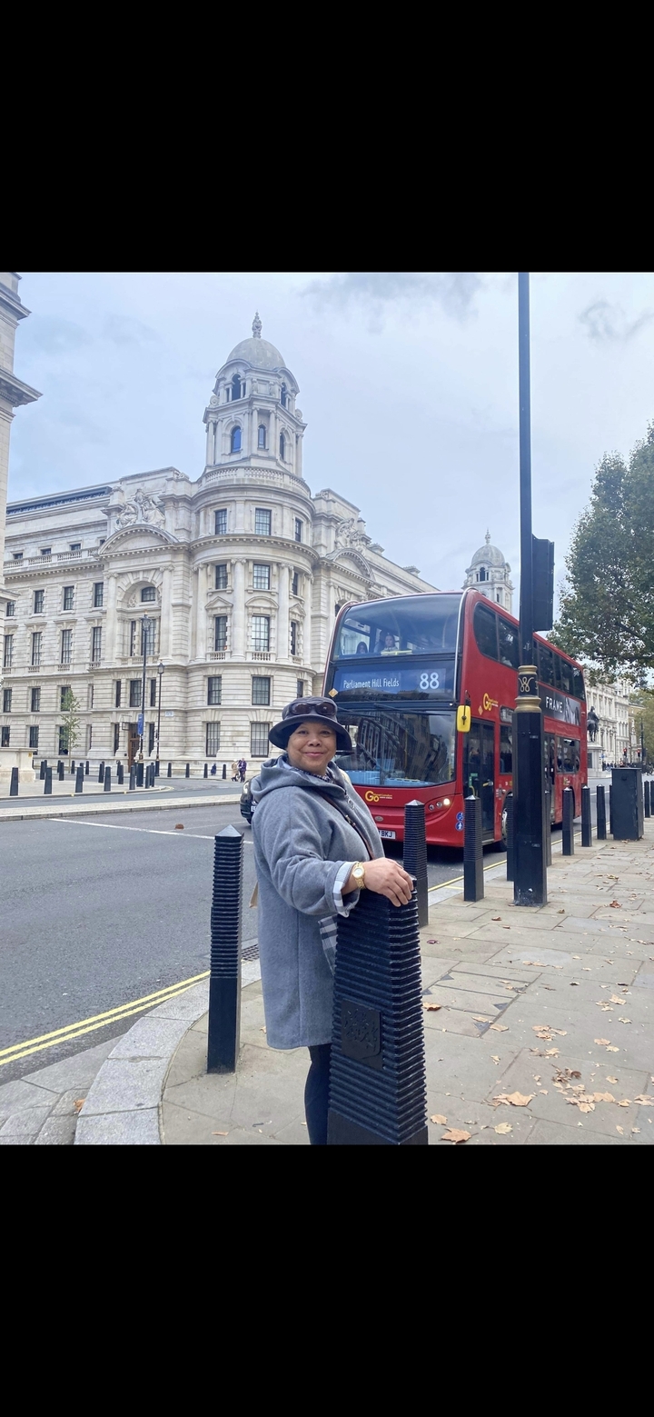 Personne posant près d'un bus à impériale rouge dans une rue de la ville.