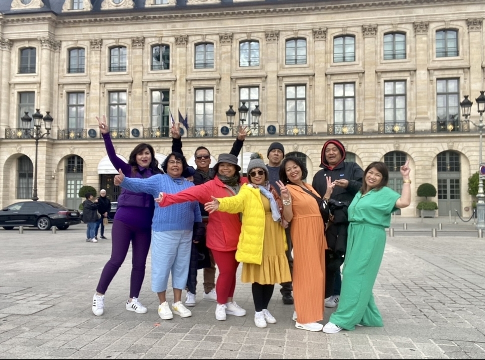Groupe posant devant un grand bâtiment historique sur une place de la ville.