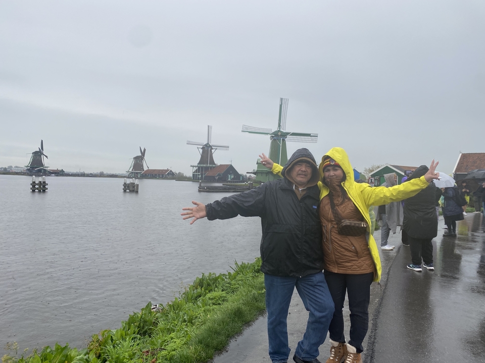Couple posant avec des moulins à vent en arrière-plan.
